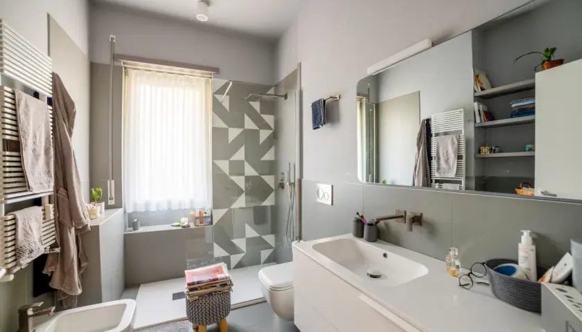 Bagno moderno con doccia su finestra, lavabo, bidet e scalda-asciugamani.