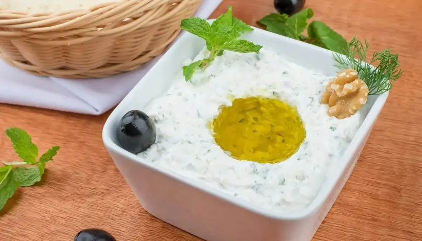 Pyszny sos tzatziki z oliwą, miętą, orzechem i oliwkami, gotowy do podania z pitą z koszyka.