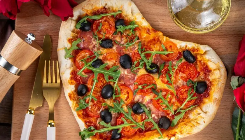 Pizza w kształcie serca z pomidorami, oliwkami i rukolą. Idealna na romantyczną kolację w domu, co ugotować?