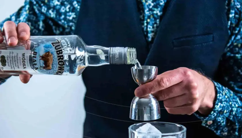 Wybierasz jaka wódka na wesele? Żubrówka Biała idealna do drinków, nalewana przez barmana do kieliszka z lodem.