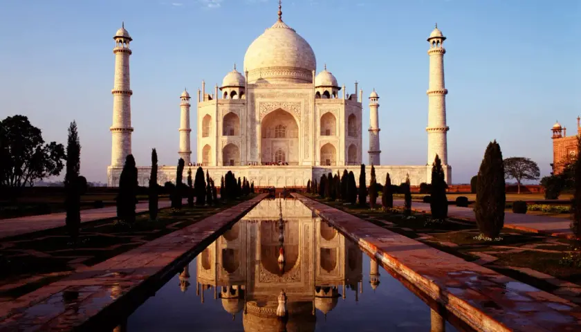 Der Taj Mahal, eine Moschee und ein Mausoleum, spiegelt sich im Wasser.