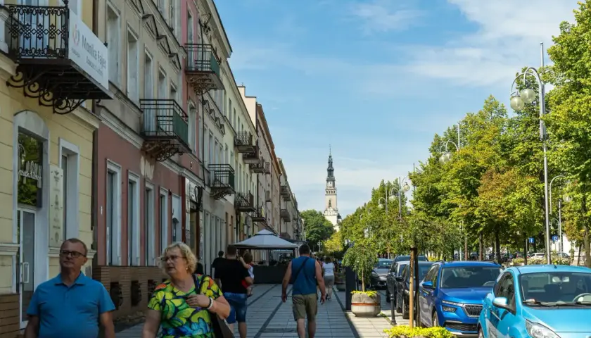 Spacerem ulicą w Częstochowie, w oddali widać wieżę Jasnej Góry. Trasa pielgrzymkowa tętni życiem.