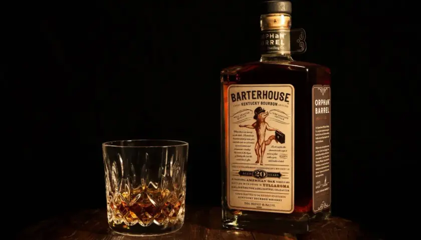 Verre de bourbon ambré et bouteille Orphan Barrel Barterhouse 20 ans. Une dégustation pour apprécier la différence whiskey bourbon.