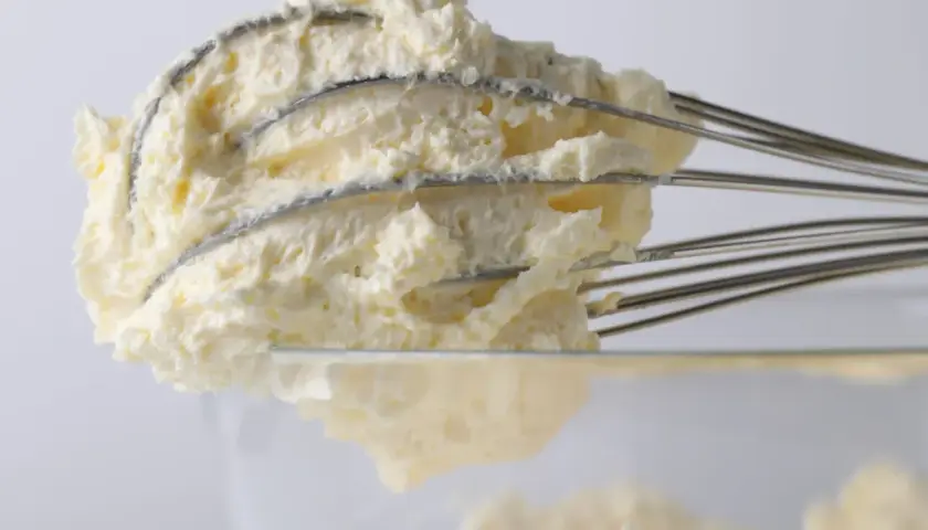 Puszysty krem mascarpone na drucianej trzepaczce, gotowy do deserów.