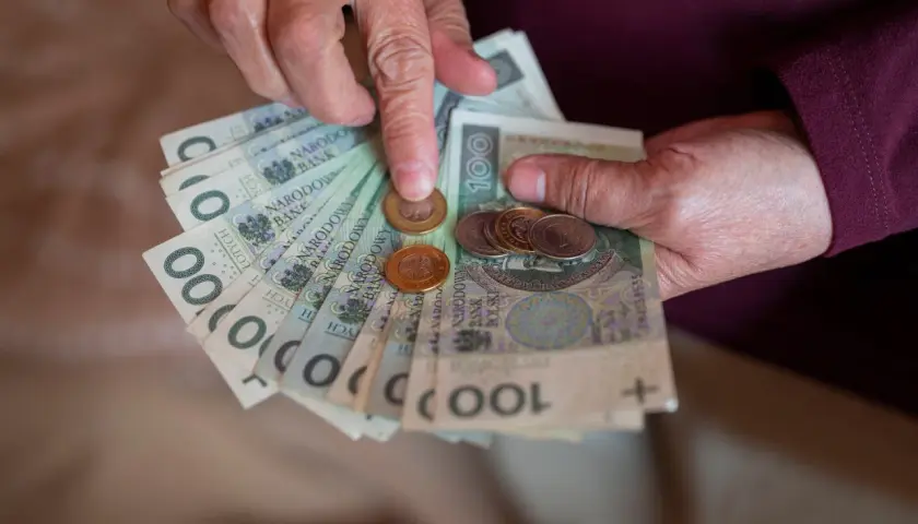 Dłonie liczą banknoty i monety. Warto sprawdzić 13 emerytura tabela 2026, by poznać przyszłe świadczenia.