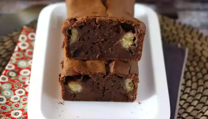 Dos porciones de bizcocho de plátano y chocolate apiladas, con trozos de plátano visibles en su interior.