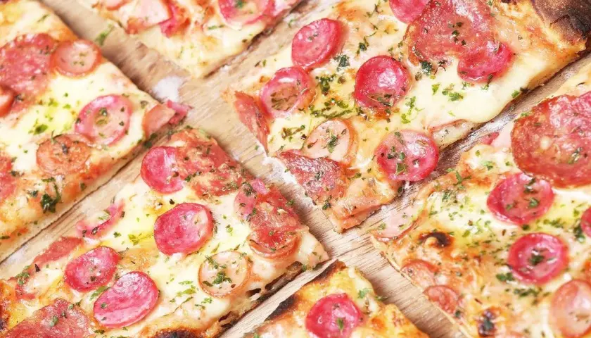Kawałki pysznej, gorącej pizza włoska z kiełbasą i serem, posypane ziołami. Idealna na spotkanie z przyjaciółmi.