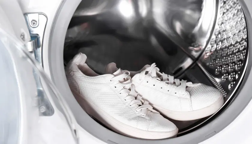 Paire de baskets blanches dans le tambour d'une machine à laver.