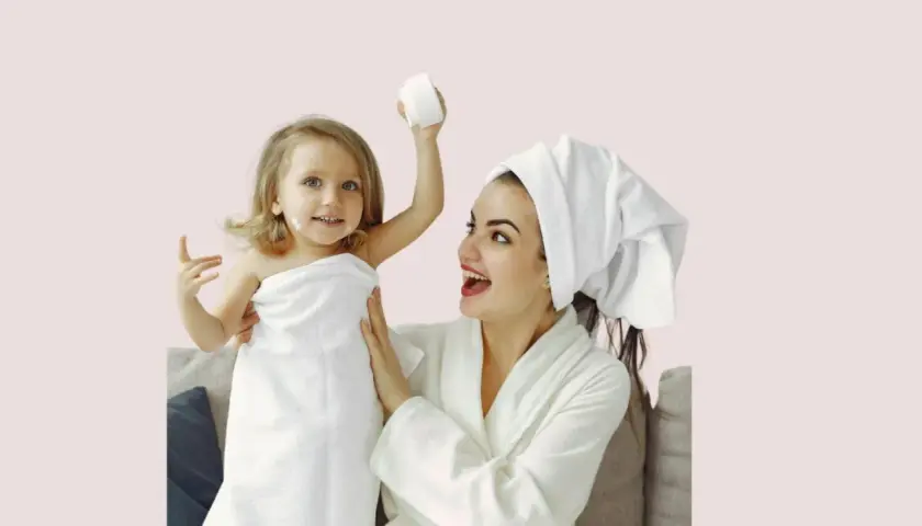 Mère et fille profitent d'un moment de **soin du visage pour petite fille fait maison**. La petite est enroulée dans une serviette, avec de la crème sur le nez.