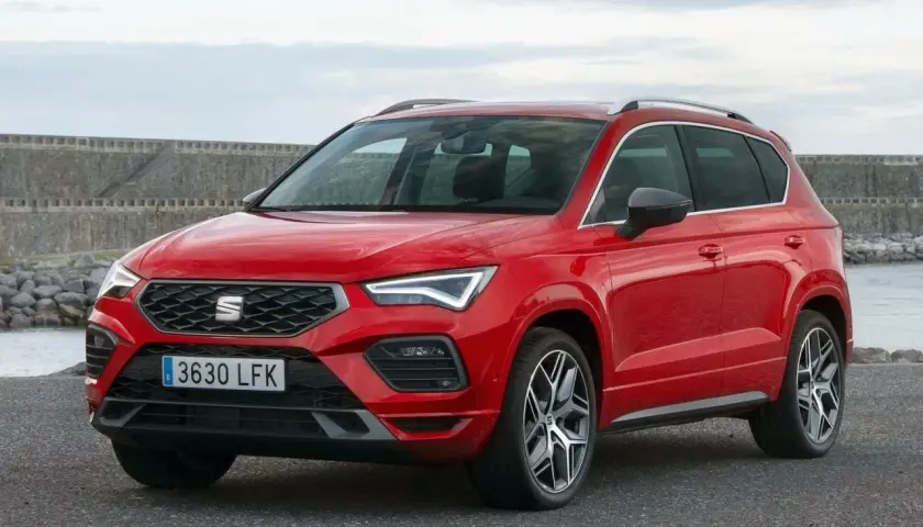 Czerwony Seat Ateca na tle kamiennego nabrzeża. Wiele osób szuka seat ateca opinie przed zakupem.