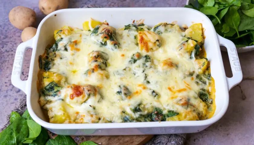 Ein köstlicher Kartoffel-Spinat-Auflauf mit geschmolzenem Käse, bereit zum Servieren. Frische Kartoffeln und Spinat sind die Basis dieses herzhaften Gerichts.
