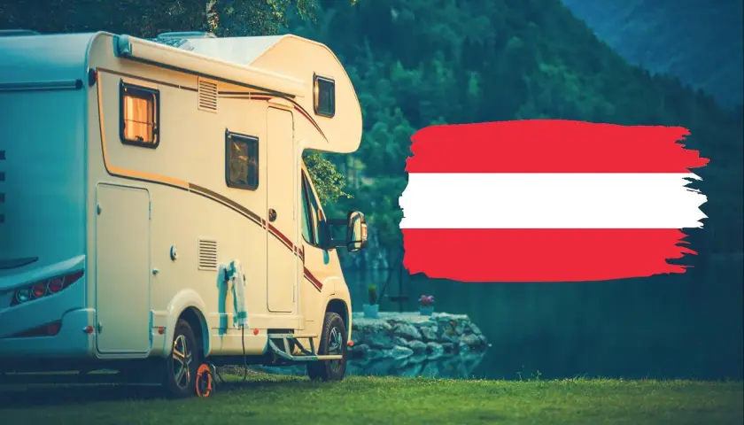 Kamper zaparkowany nad jeziorem w Karyntii, Austria. Obok flaga Austrii.