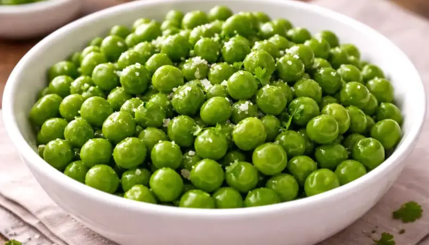 Un bol de petits pois frais, brillants et assaisonnés de sel et de persil, prêts pour la cuisson.