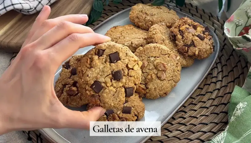 Mano tomando una galleta de avena con trozos de chocolate. Deliciosas galletas de avena caseras.