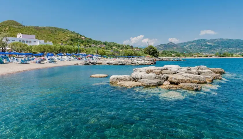 Spiaggia attrezzata con ombrelloni e lettini, mare cristallino e rocce affioranti. Un angolo di paradiso nel Cilento, mare da sogno.