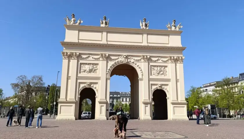 Brama Brandenburska w Poczdamie, gdzie leży to piękne miasto, z ludźmi i psami na placu.