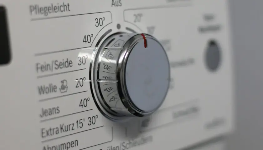 Drehknopf einer Waschmaschine mit verschiedenen Waschprogrammen wie Pflegeleicht, Fein/Seide, Wolle und Jeans.