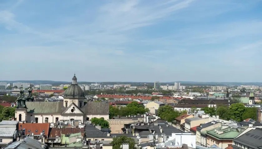 Widok na krakowskie dachy i kościół z kopułą. W tle nowoczesne budynki, które mogą wpływać na ceny mieszkań Kraków.