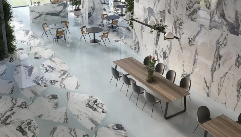 Interni eleganti con pavimenti e pareti che richiamano i **marmo di Carrara colori** con venature grigie e bianche, tavoli e sedie moderne.
