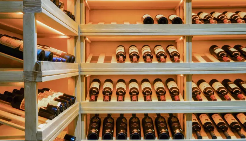 Étagères en bois remplies de bouteilles de vin, parfait pour faire sa cave à vin.