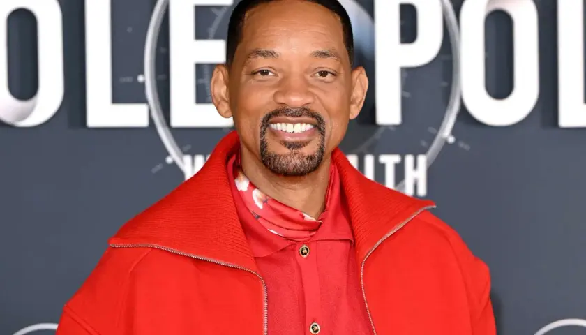 Will Smith, souriant, porte une veste rouge vif. On peut lire "POLE" en lettres blanches derrière lui, suggérant son prochain film.