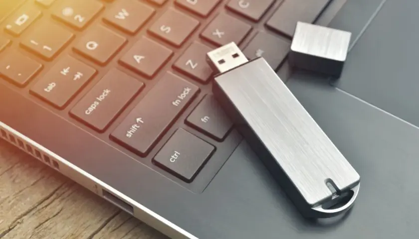 Silberner USB-Stick liegt auf einer Laptop-Tastatur. Vielleicht hilft das, den USB-Stick RAW zu reparieren.
