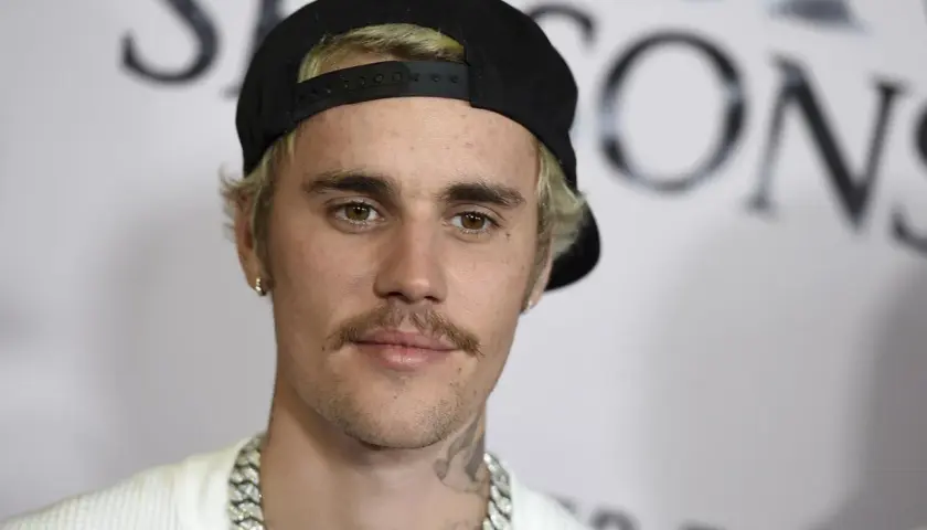 Justin Bieber w czapce z daszkiem i z wąsami, wygląda jakby świętował swoje urodziny.