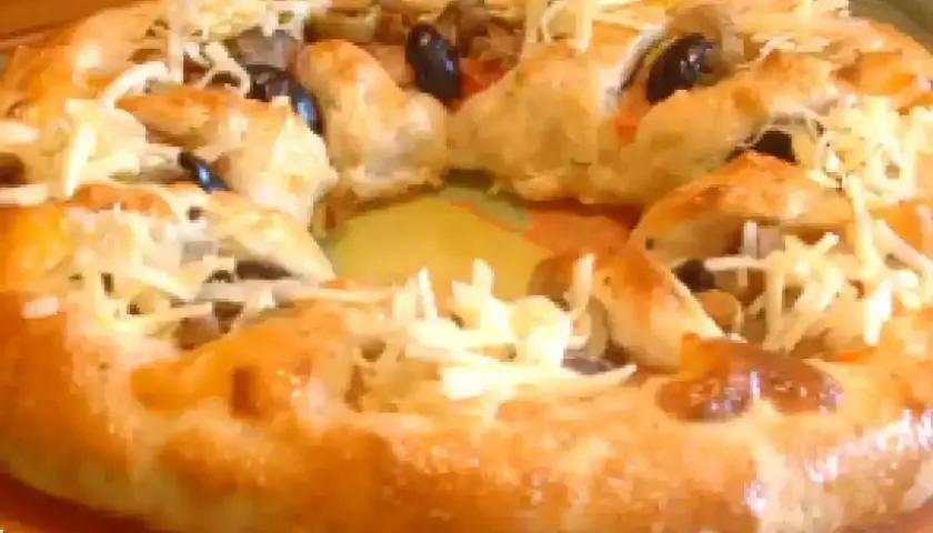 Pizza maison avec une croûte dorée, garnie d'olives noires et de fromage râpé. Parfait pour une recette pâte à pizza rapide.
