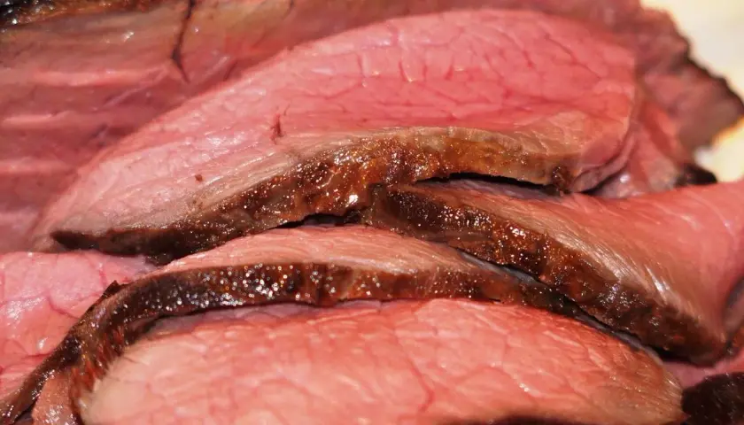 Tranches de rosbeef juteuses, parfaitement saisies, révélant une cuisson rosée idéale. Un délice pour les amateurs de viande.