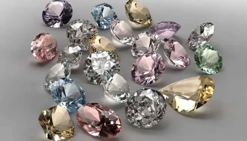 Bunte Edelsteine, was ist wertvoller als Diamant? Ein Haufen funkelnder, geschliffener Juwelen in Rosa, Blau, Grün und Gelb.