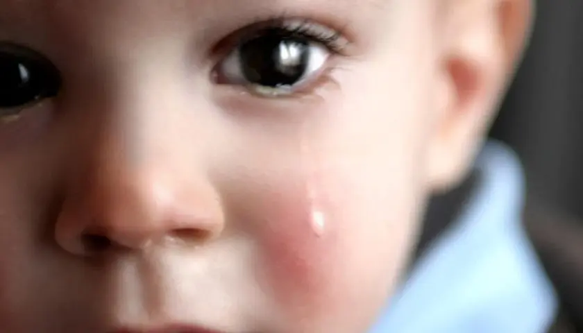 Un bambino piange, una lacrima scende sulla sua guancia arrossata. L'orzaiolo sui suoi occhietti lo fa soffrire.
