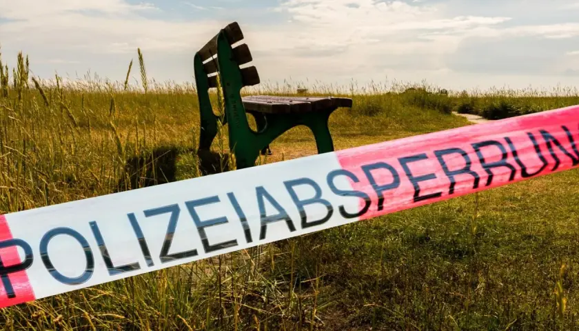 Polizeisperrband vor einer grünen Parkbank in einer Wiese. Ein Tatort, der Stoff für die besten Regionalkrimis liefert.