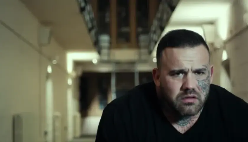 Martyn Ford, acteur aux multiples tatouages, dans un couloir sombre. Une scène qui pourrait figurer dans ses films.