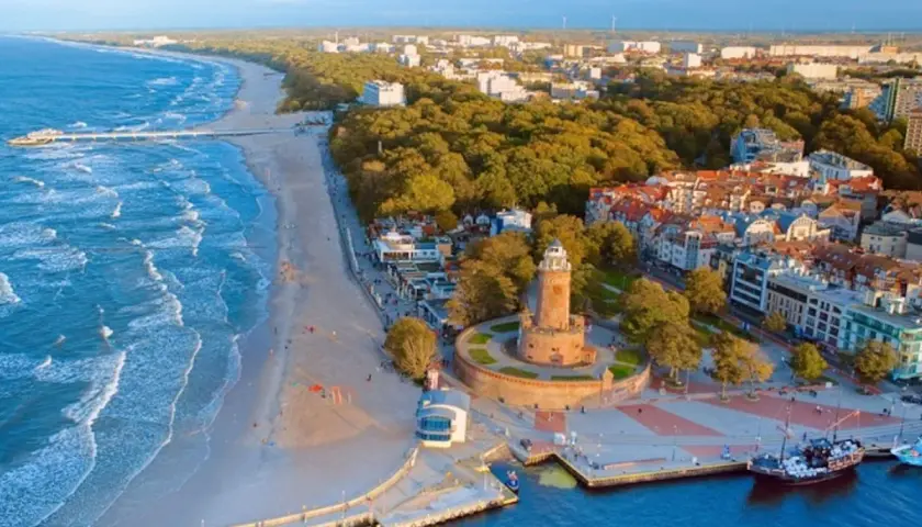 Malownicza miejscowość nad morzem z latarnią morską, plażą i molo.