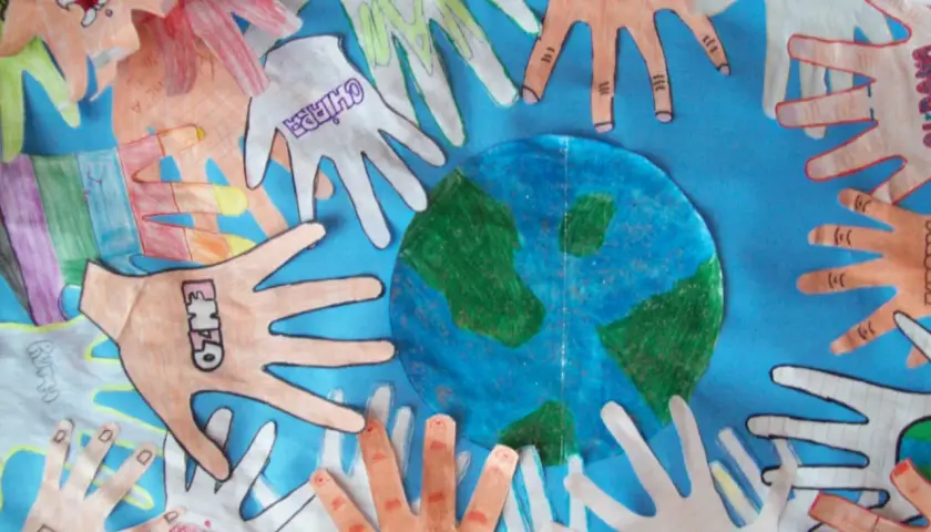 Manos de niños alrededor del planeta Tierra, celebrando actividades del Día de la Tierra.