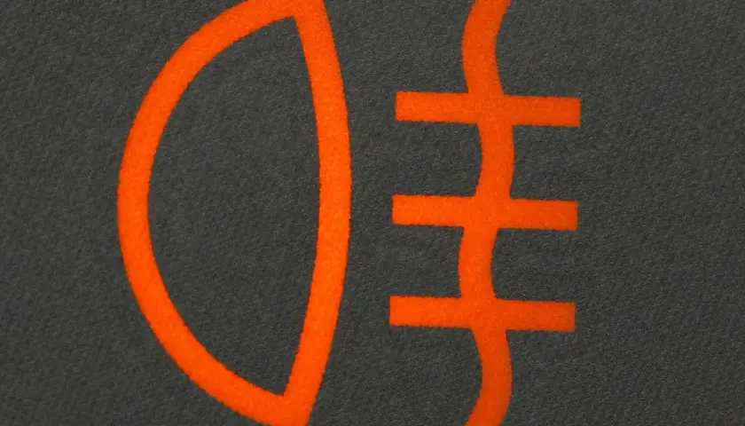 Pomarańczowy symbol świateł dziennych na ciemnym tle.