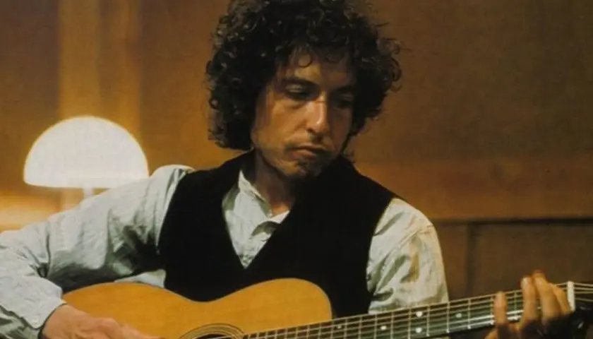 Bob Dylan gra na gitarze, tworząc ponadczasowe utwory.