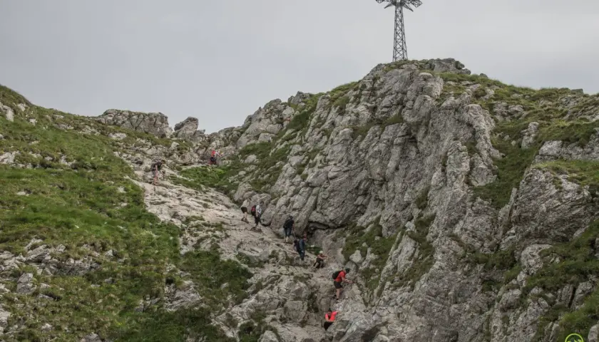 Grupa turystów wspina się po kamienistym zboczu Giewontu. Czy wejście na Giewont jest trudne? Trasa wymaga kondycji i ostrożności.