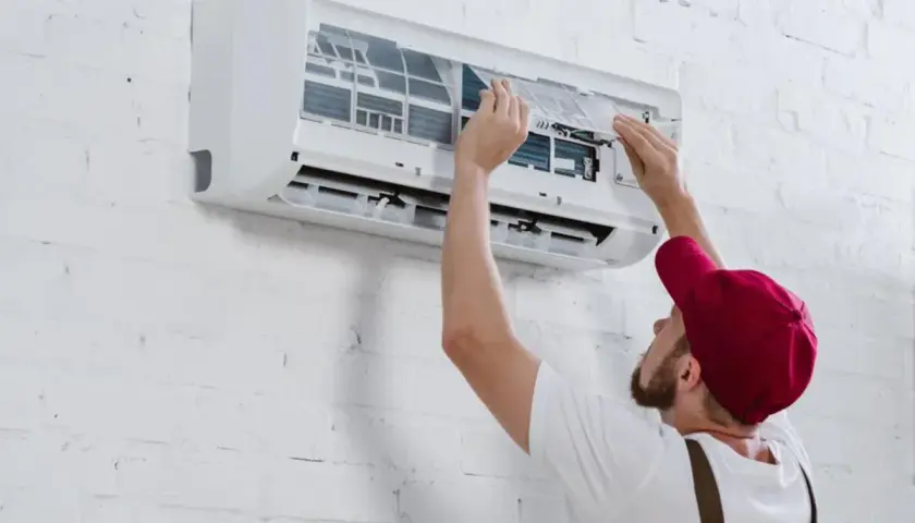 Técnico instalando un aire acondicionado inverter, ajustando filtros.