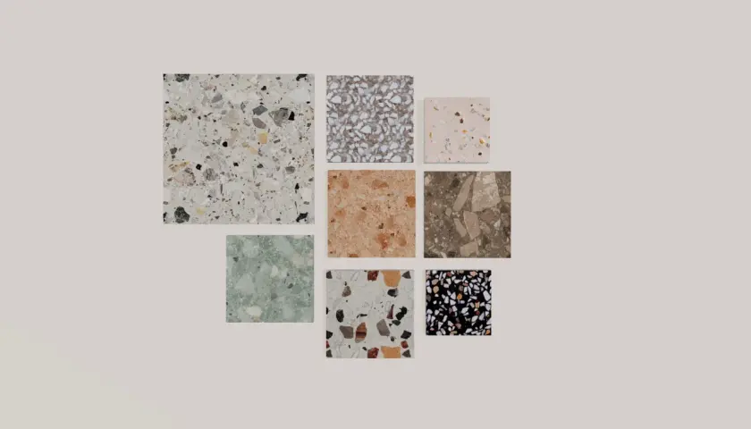 Vari campioni di piastrelle con un affascinante **effetto graniglia** in diverse colorazioni e dimensioni, dal bianco al nero, passando per tonalità naturali e pastello.