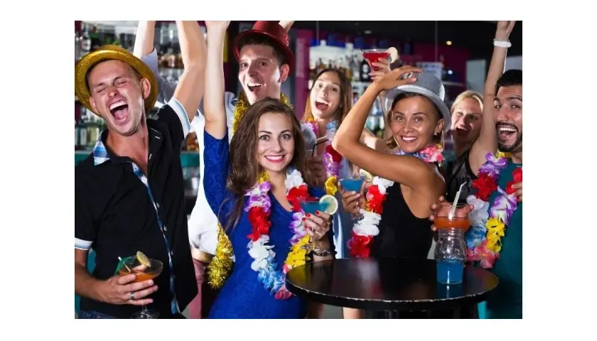 Grupa przyjaciół świętuje w stylu hawajskim, nosząc girlandy z kwiatów i drinki.