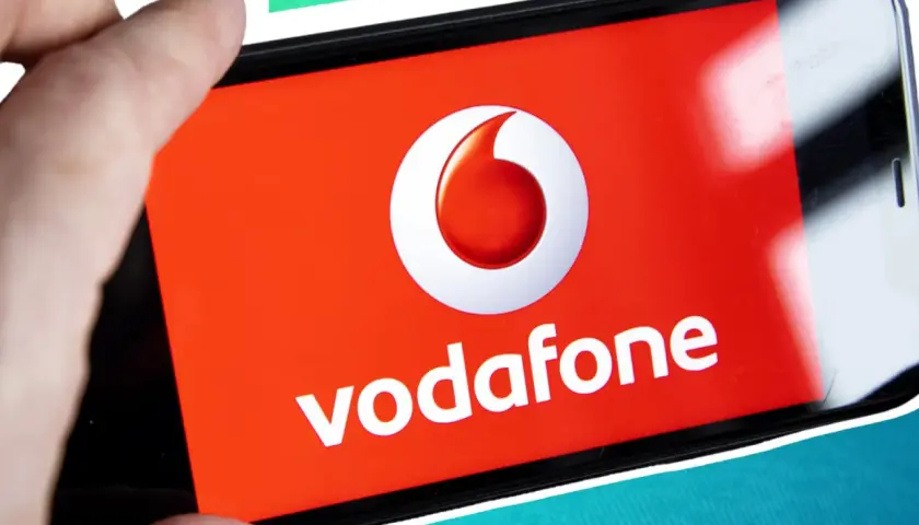 Vorsicht vor der neuen Betrugsmasche Vodafone! Ein Finger hält ein Smartphone mit dem Vodafone-Logo.