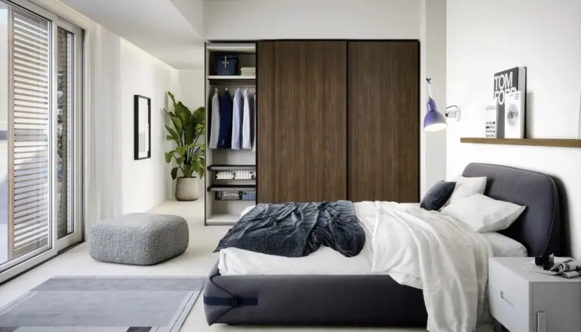 Elegante camera da letto piccola con letto matrimoniale, armadio a muro in legno scuro, pouf e tappeto grigio.