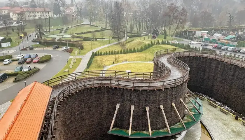 Wieliczka miasto. Drewniane tężnie solankowe tworzą malowniczą spiralę, a w tle widać zabudowania i park.