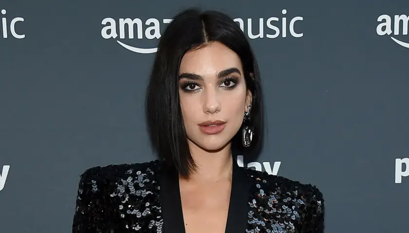 Mujer con un elegante corte pelo bob oscuro, maquillaje dramático y un blazer de lentejuelas.