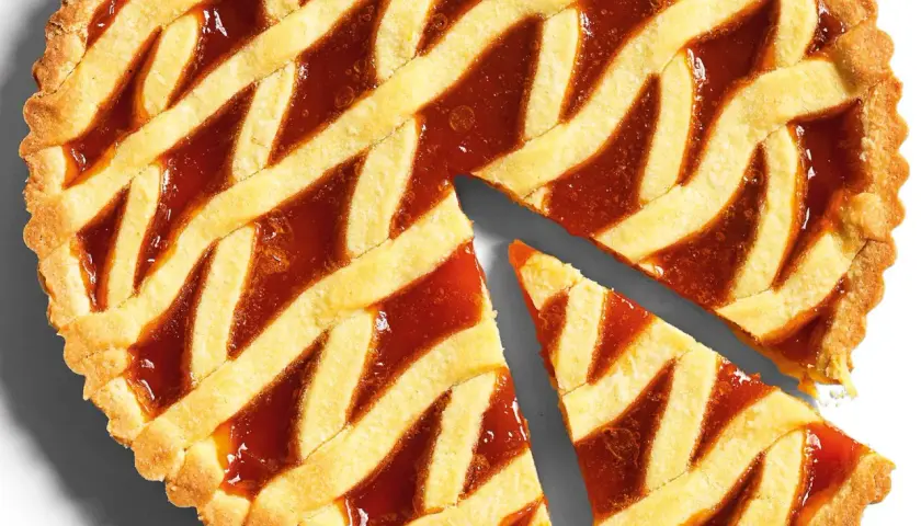 Torta con marmellata, la pasta frolla dorata e croccante è perfetta per la cottura. Due fette sono già state tagliate.