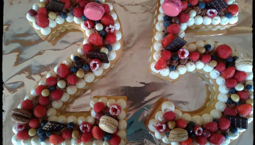Gâteau chiffre 25 décoré de chantilly mascarpone, framboises, fraises, myrtilles, macarons et chocolat.