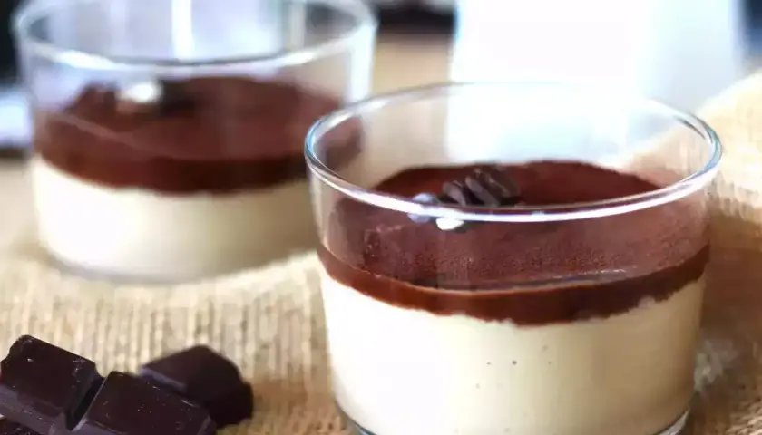 Deliziosa ganache al caffè espresso in bicchierini, guarnita con cacao e chicchi di caffè. Accanto, pezzi di cioccolato fondente.