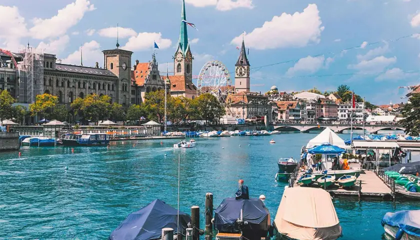 Widok na Zurych, największe miasto Szwajcarii, z rzeką Limmat, łodziami i zabytkową architekturą.