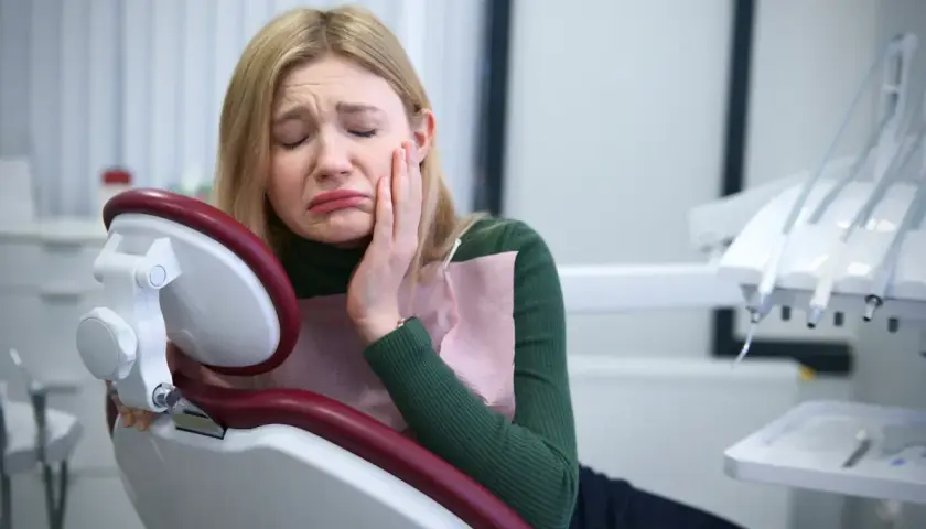 Dziewczyna cierpi na okropny ból zęba, szukając pomocy u dentysty.